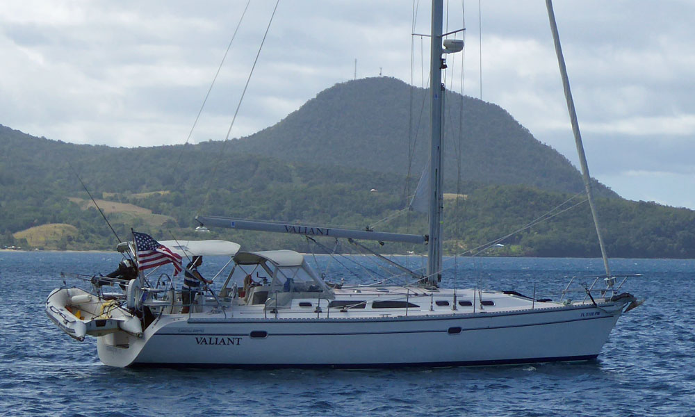 A Catalina 400 sailboat motoring out of the Portsmouth anchorage in Dominica.