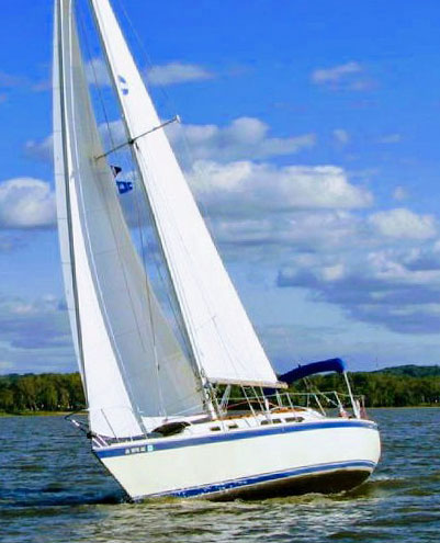 An O'Day 30 sailboat beating to windward under full sail