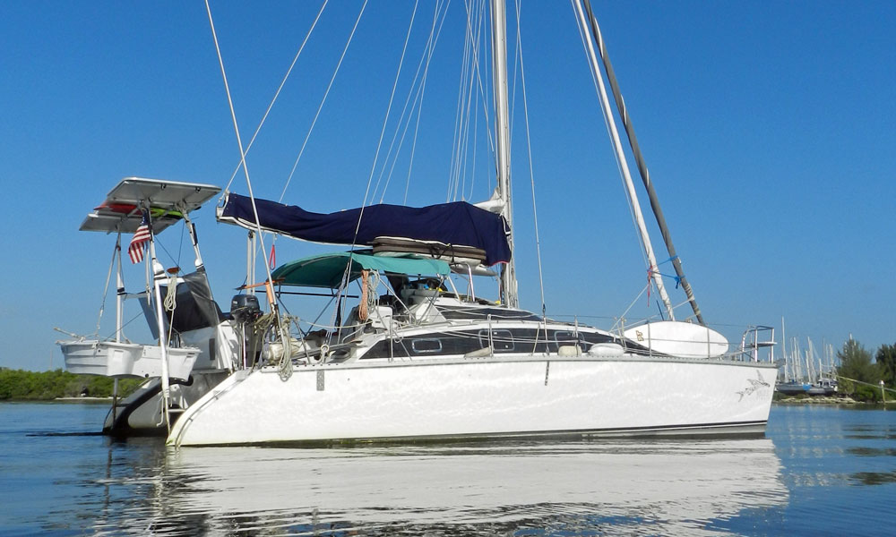 A PDQ 36 catamaran at anchor, with the dinghy supported in davits