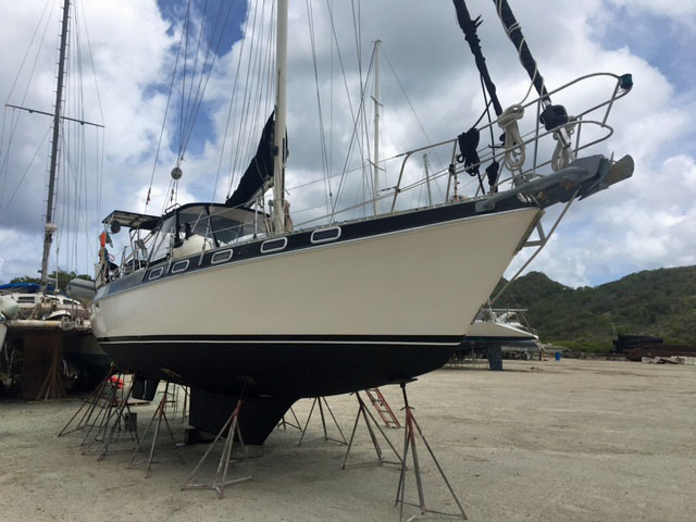 A Morgan 41 Classic sailboat on tripod stands ashore in a boatyard