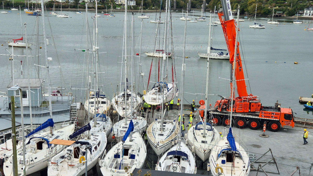 Sailboats being craned out for winter storage ashore at the end of the sailing season.