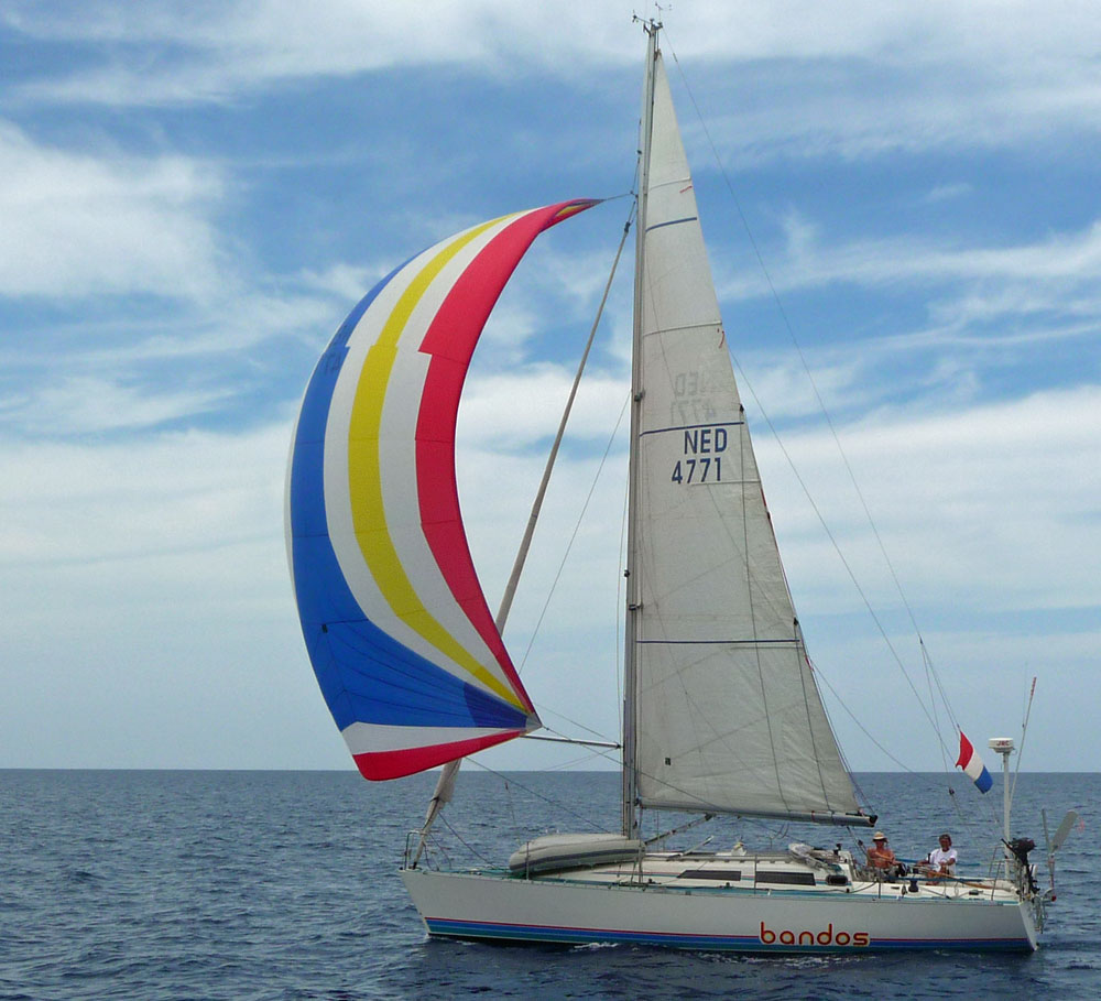 A fractionally rigged cruising boat flying a conventional spinnaker